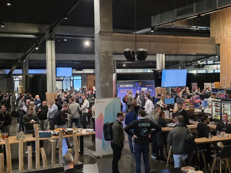 A packed expo floor with attendees gathered around the partner stands